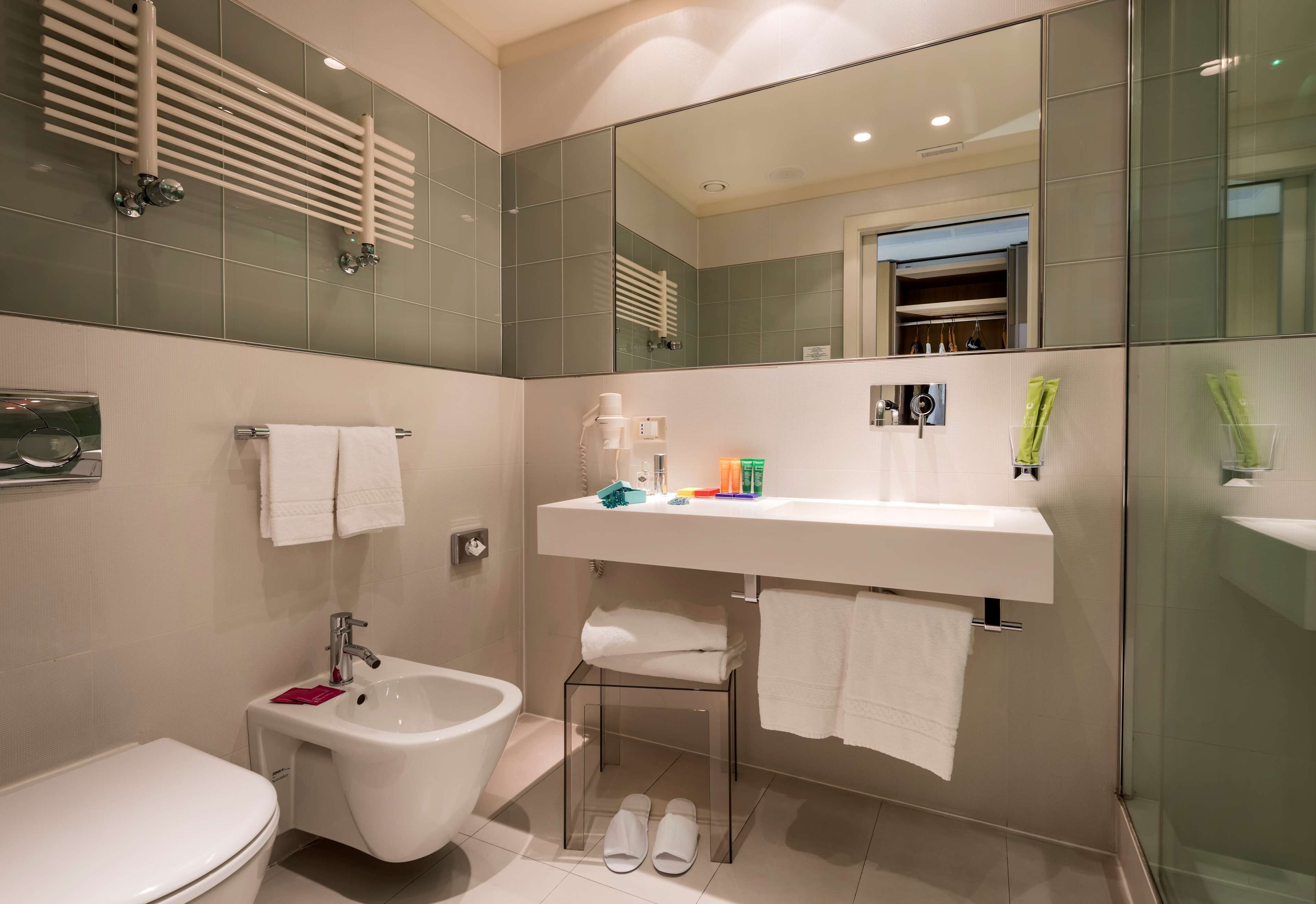 A modern bathroom with a toilet, bidet, and glass shower enclosure.