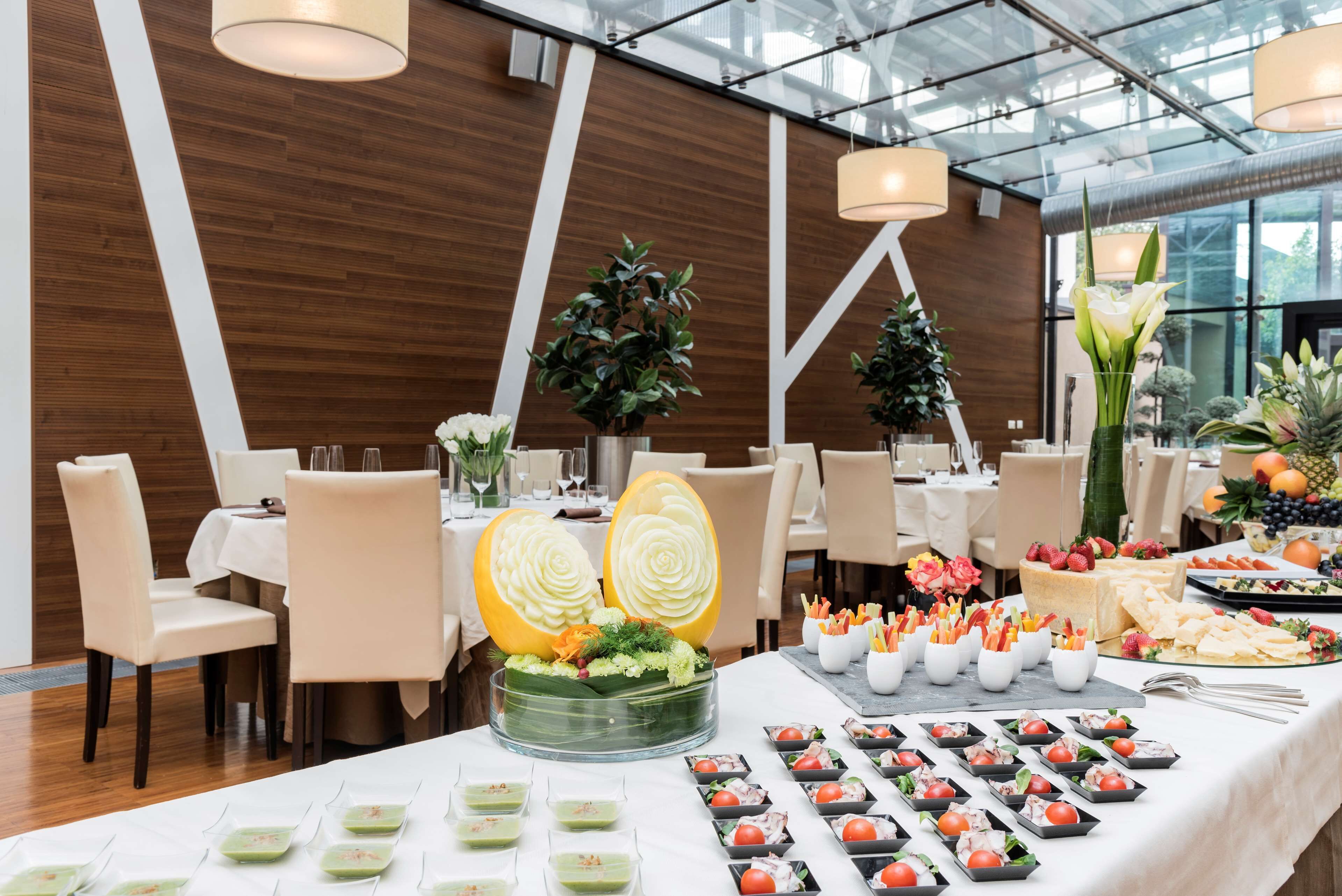 Ein Essbereich mit Tischen, die für ein Buffet gedeckt sind, mit einer Auswahl an Speisen und dekorativen Mittelpunkten.