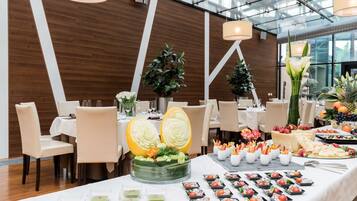 Ein Essbereich mit Tischen, die für ein Buffet gedeckt sind, mit einer Auswahl an Speisen und dekorativen Mittelpunkten.