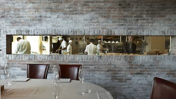 Un restaurant avec un mur en briques et un grand miroir qui reflète l’espace cuisine.