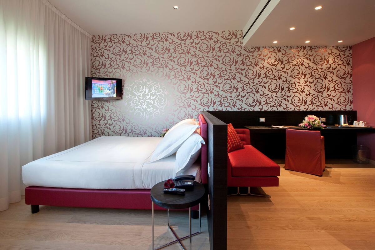 Een moderne hotelkamer met een groot bed, een bureau en een rode bank.