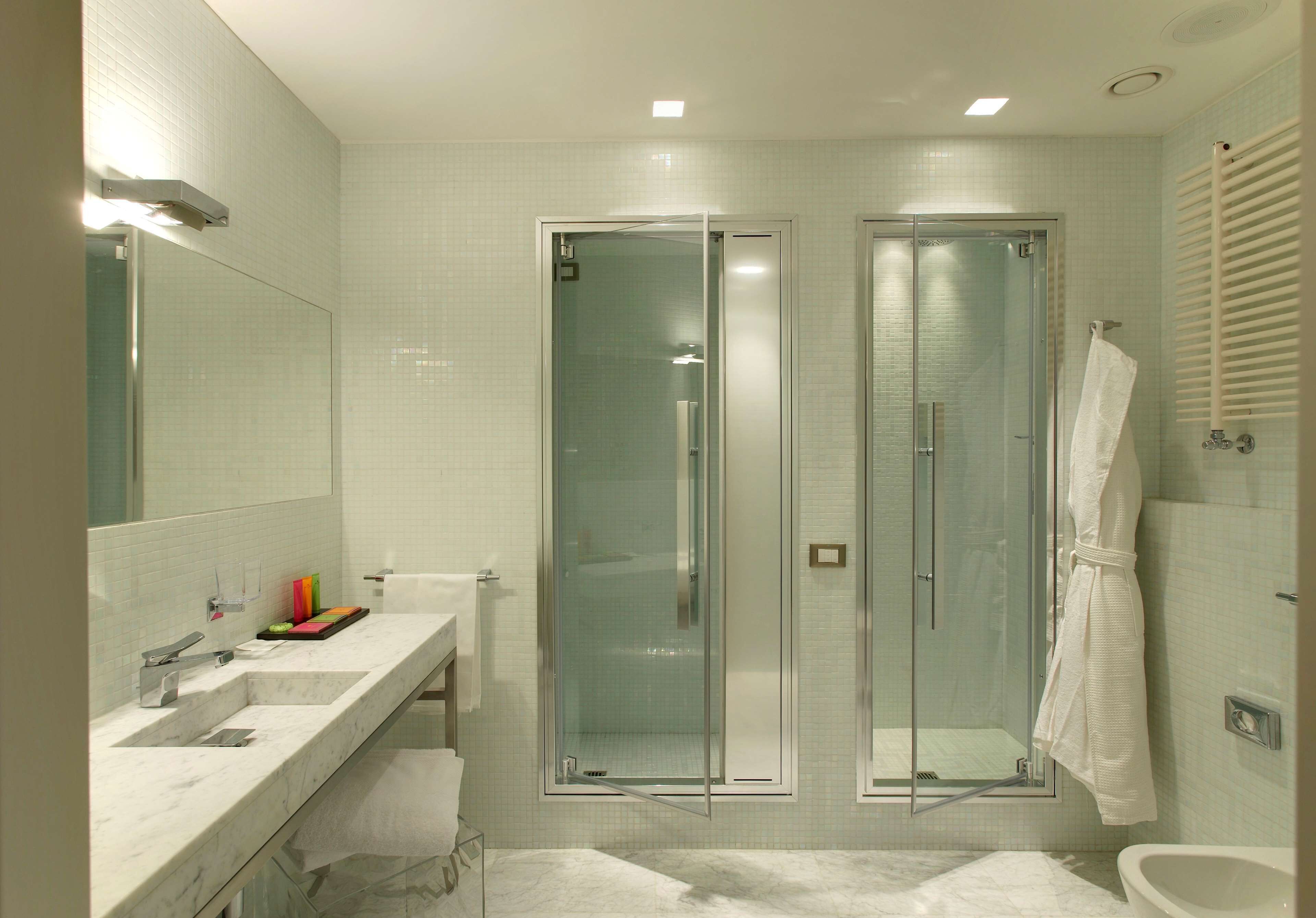 A modern bathroom with two glass-enclosed showers, a large mirror, and a white sink.