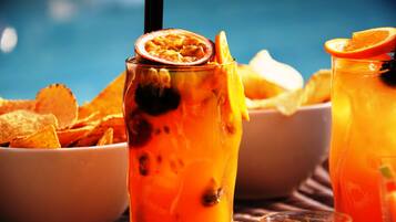 Un verre d’une boisson orangée, garnie d’une tranche de fruit de la passion et d’une tranche d’orange, accompagné d’un bol de chips de tortillas.