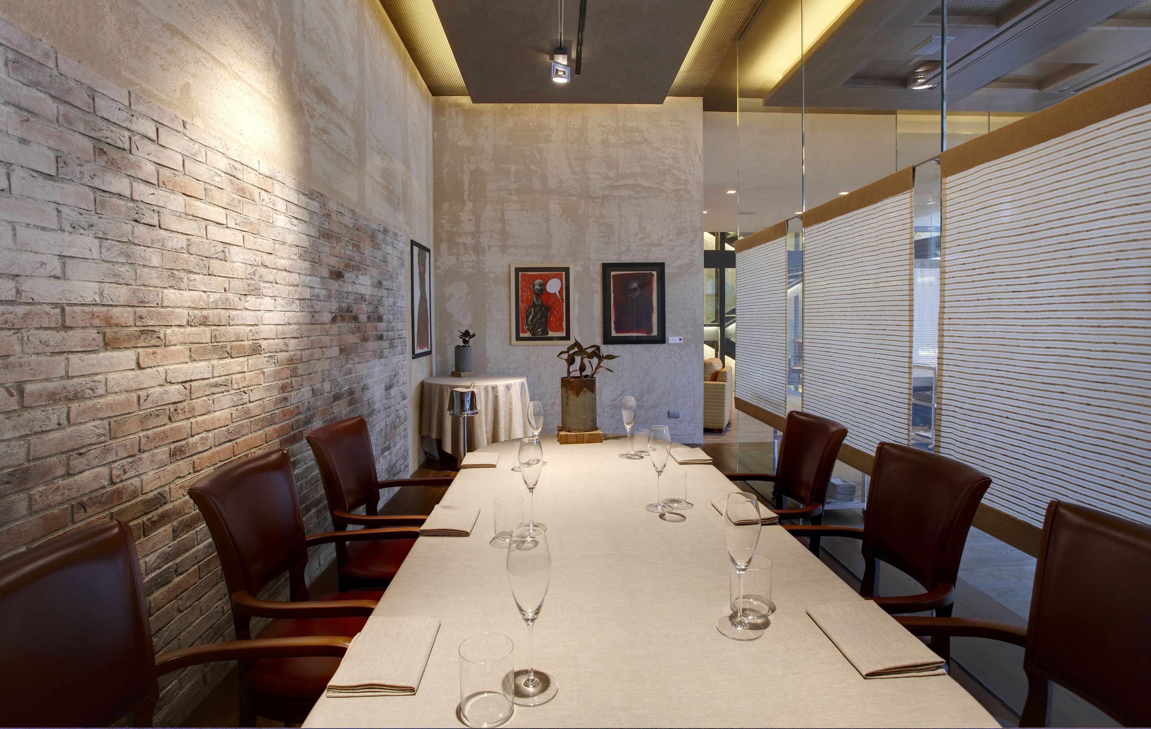 A conference room with a long table, chairs, and framed artwork on the walls.