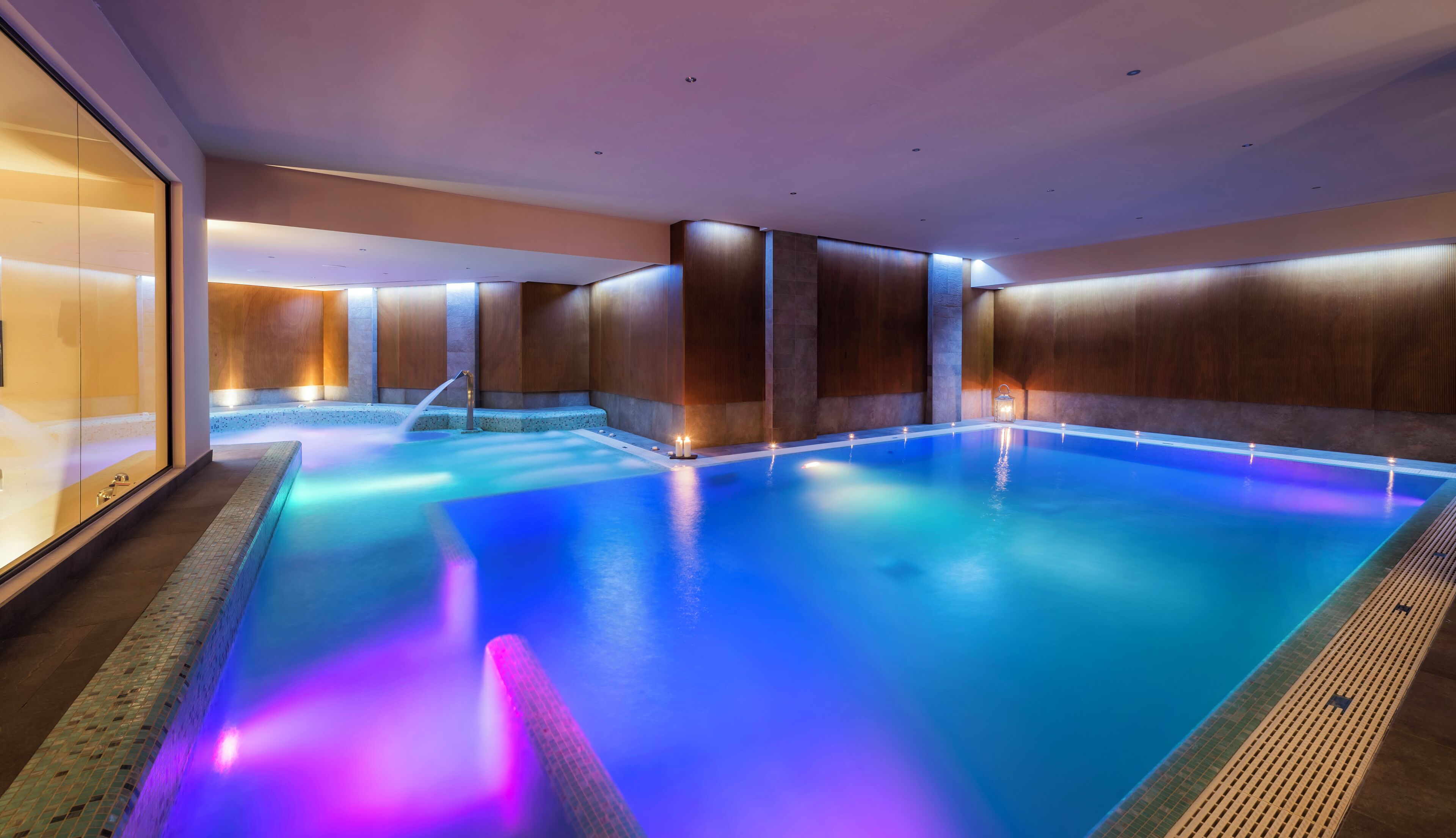 Una grande piscina coperta con pavimento piastrellato e parete laterale in legno.