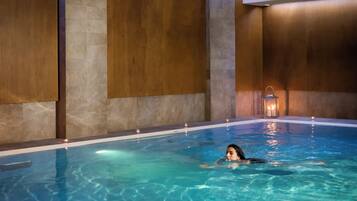 A person swimming in a pool with a candle and lantern on the edge.