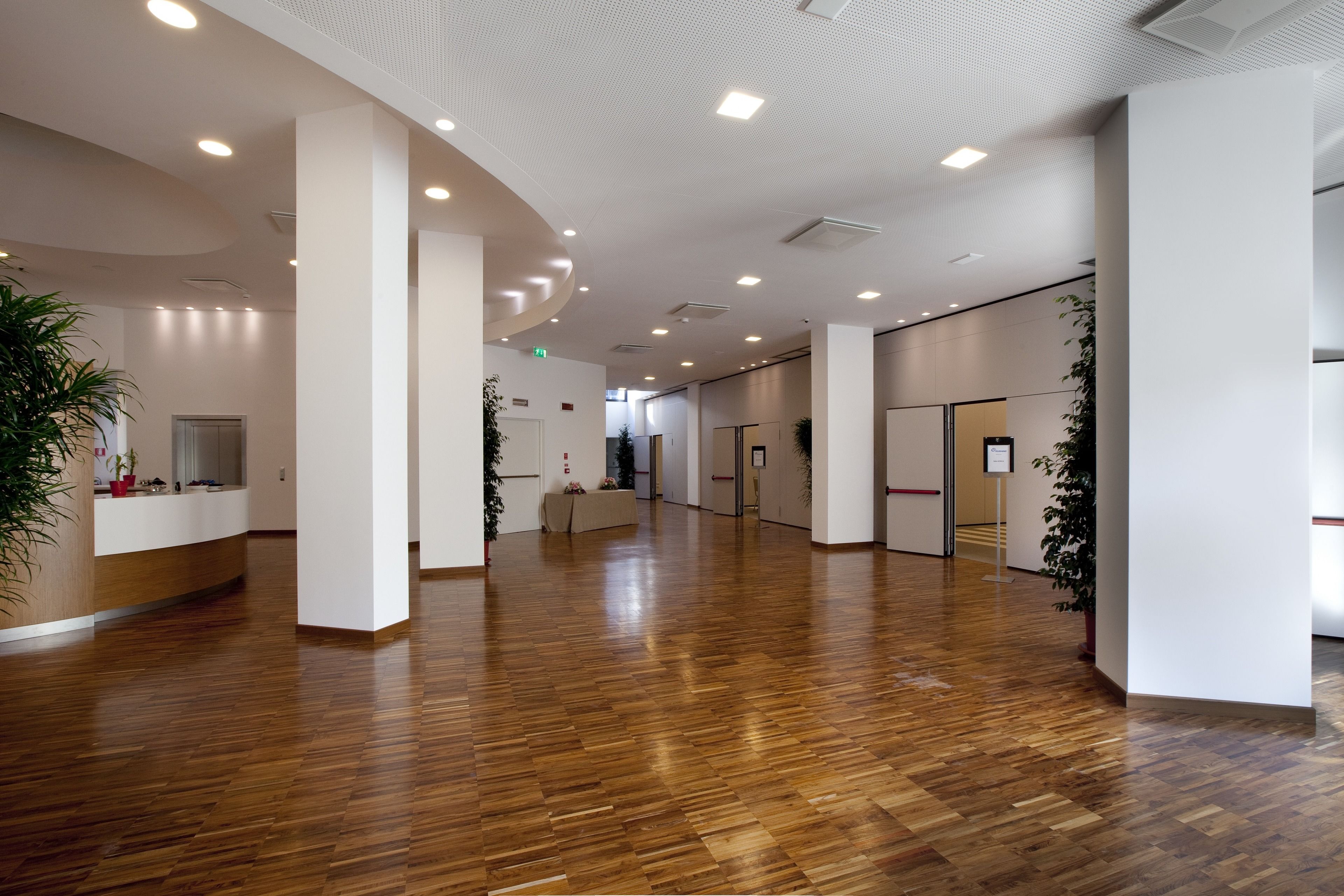 A spacious lobby with wooden flooring, white walls, and ceiling lights.