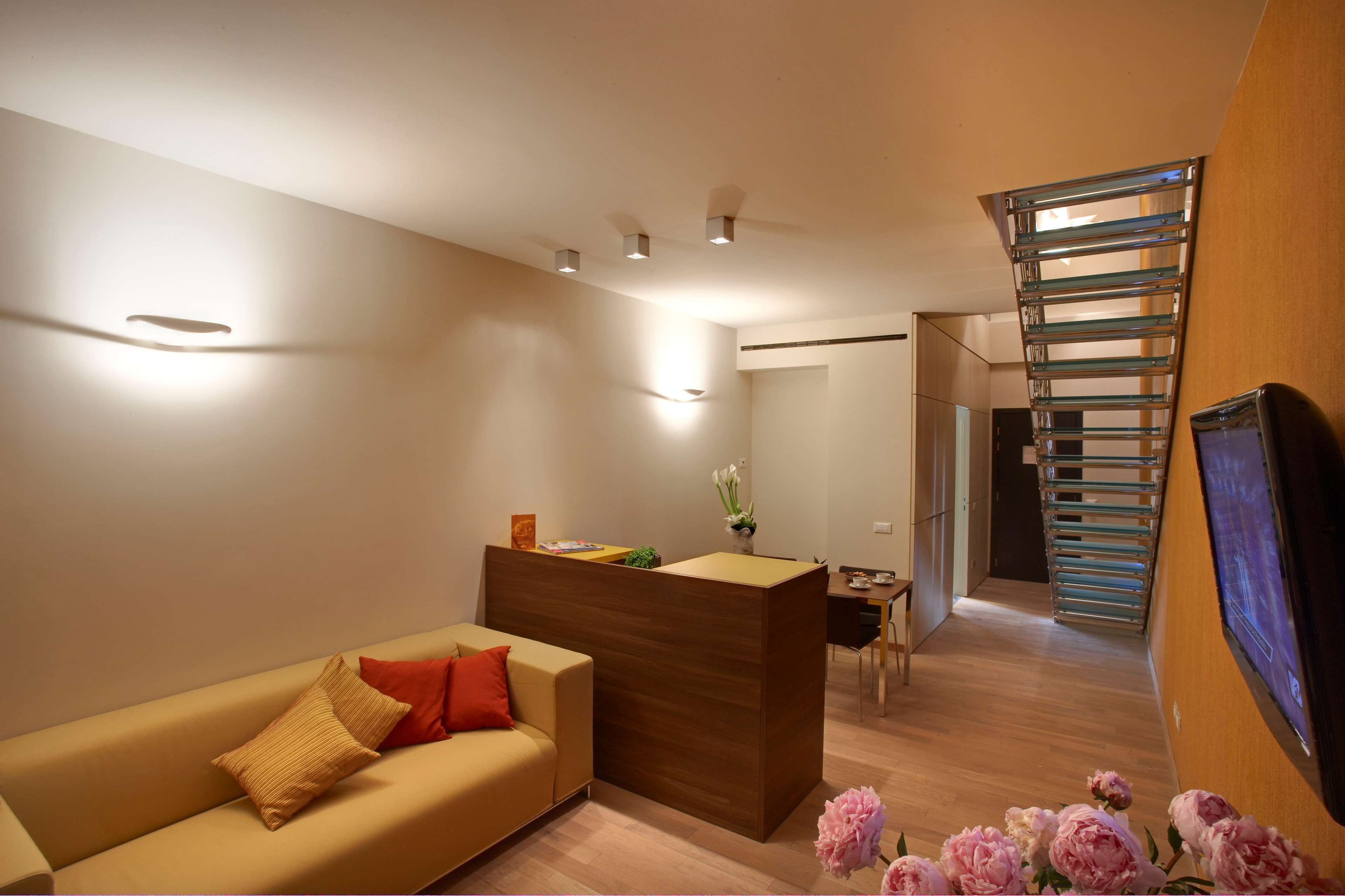 Una sala de estar moderna con un sofá, un mostrador de recepción de madera y una escalera.