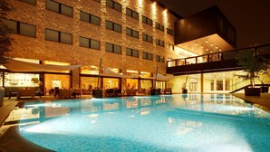 A swimming pool with a stone facade hotel in the background. - Devero Hotel & Spa, BW Signature Collection (Cavenago di Brianza)