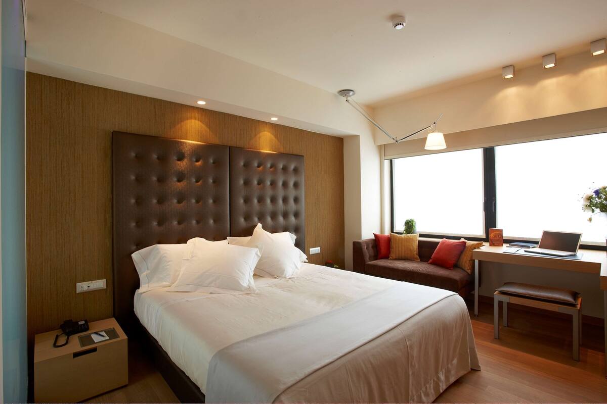 Een moderne hotelkamer met een groot bed, een bureau en een bank.