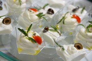 Eine Servierplatte mit Vorspeisen, cremigen Dips, Cocktailtomaten und Oliven.