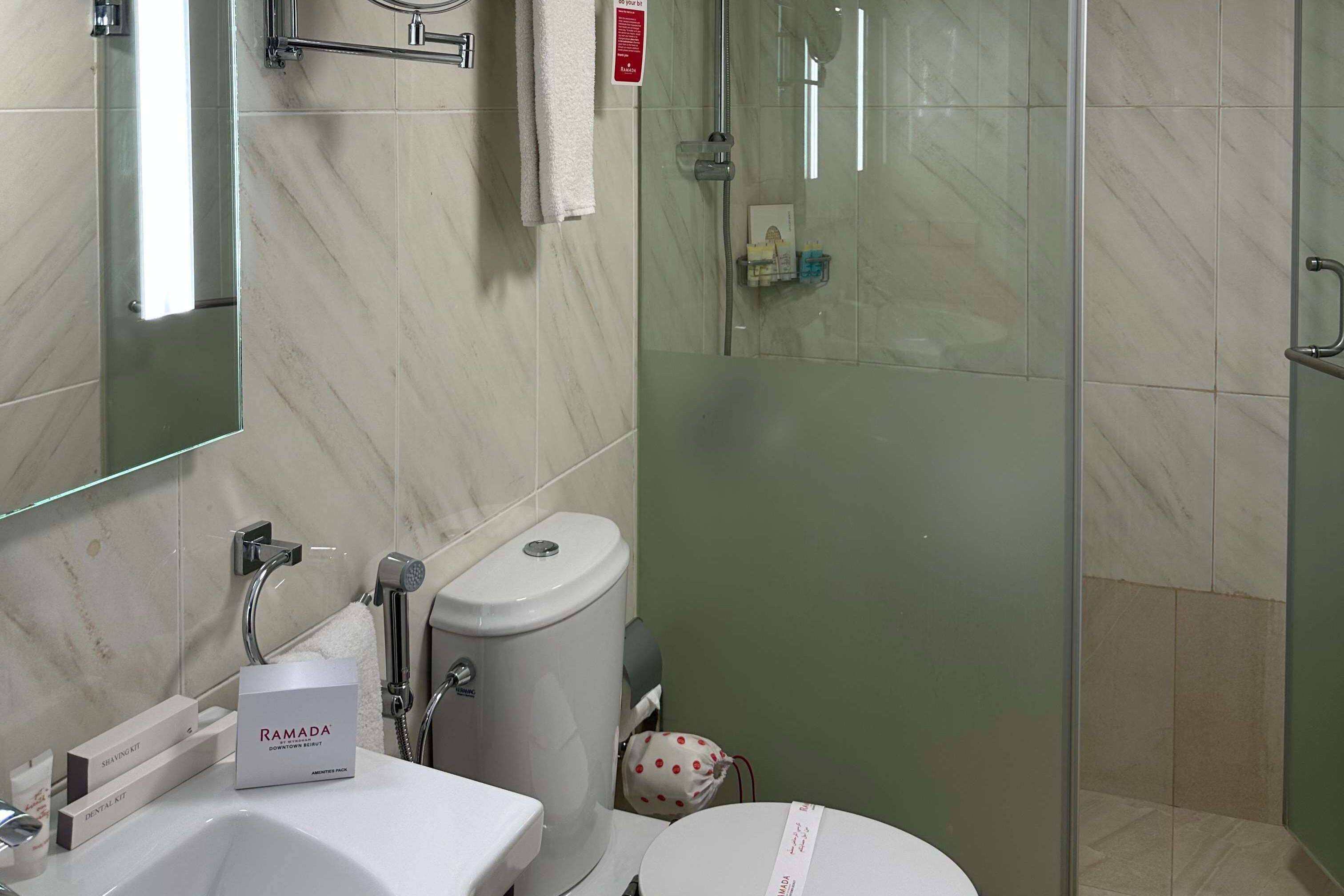 Un baño con cabina de ducha de vidrio, un lavabo blanco y un inodoro.