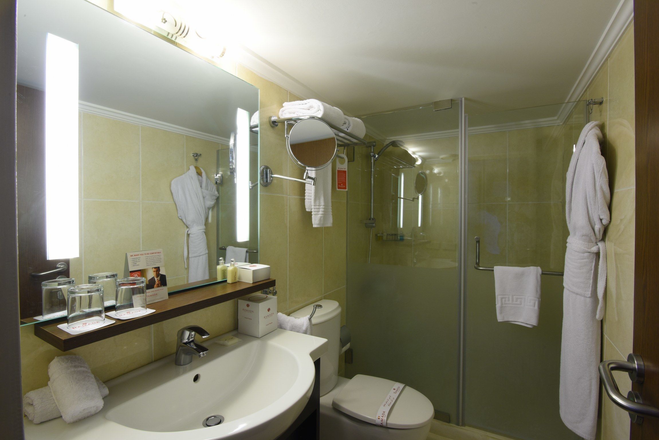 Un baño de hotel con lavamanos, inodoro y cabina de ducha de vidrio.
