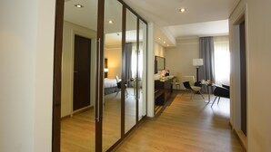 Una habitación de hotel con un gran ventanal corredera, una cama, un escritorio con una silla, una mesita y una lámpara.