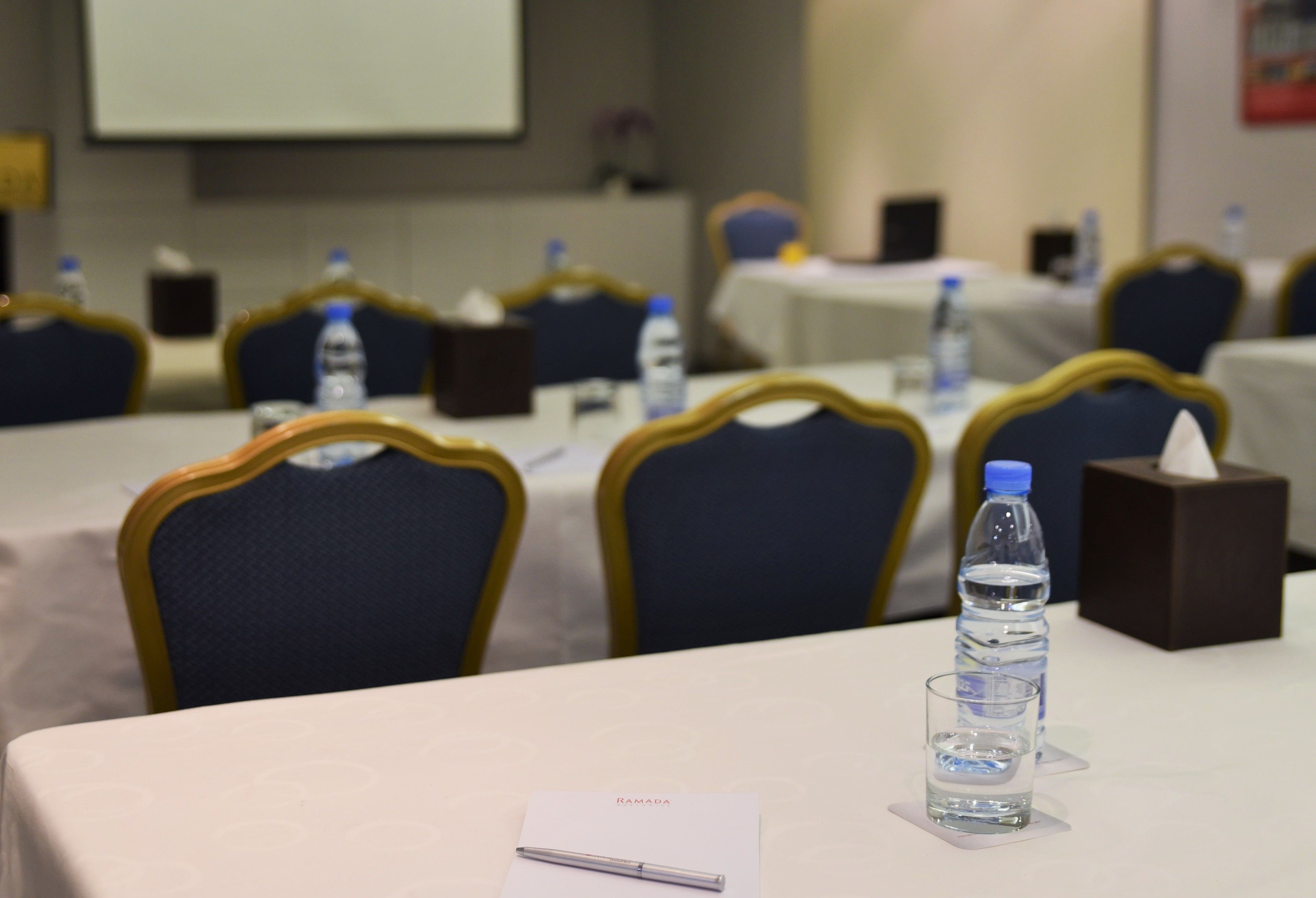 A conference room with tables set up for meetings, equipped with water bottles and tissues.