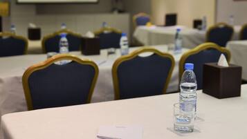 A conference room with tables set up for meetings, equipped with water bottles and tissues.