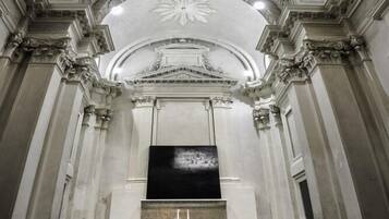 An interior with a central altar, ornate ceiling frescoes, and classical architectural details.