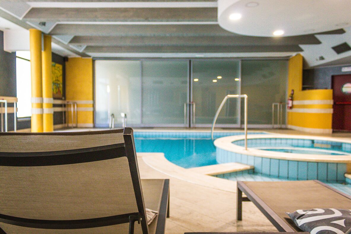 Una piscina interna con area relax, comprensiva di una poltrona e un lettino.