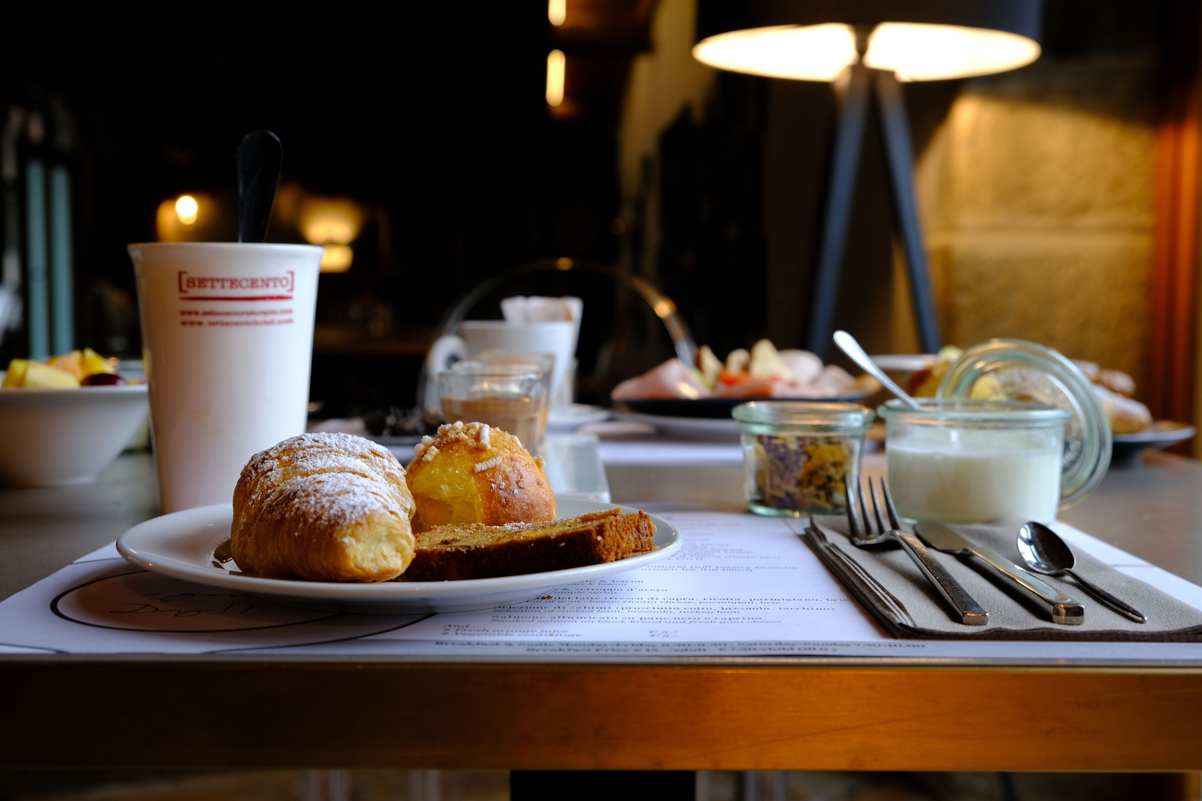 Una mesa con un plato de comida, una taza y cubiertos.