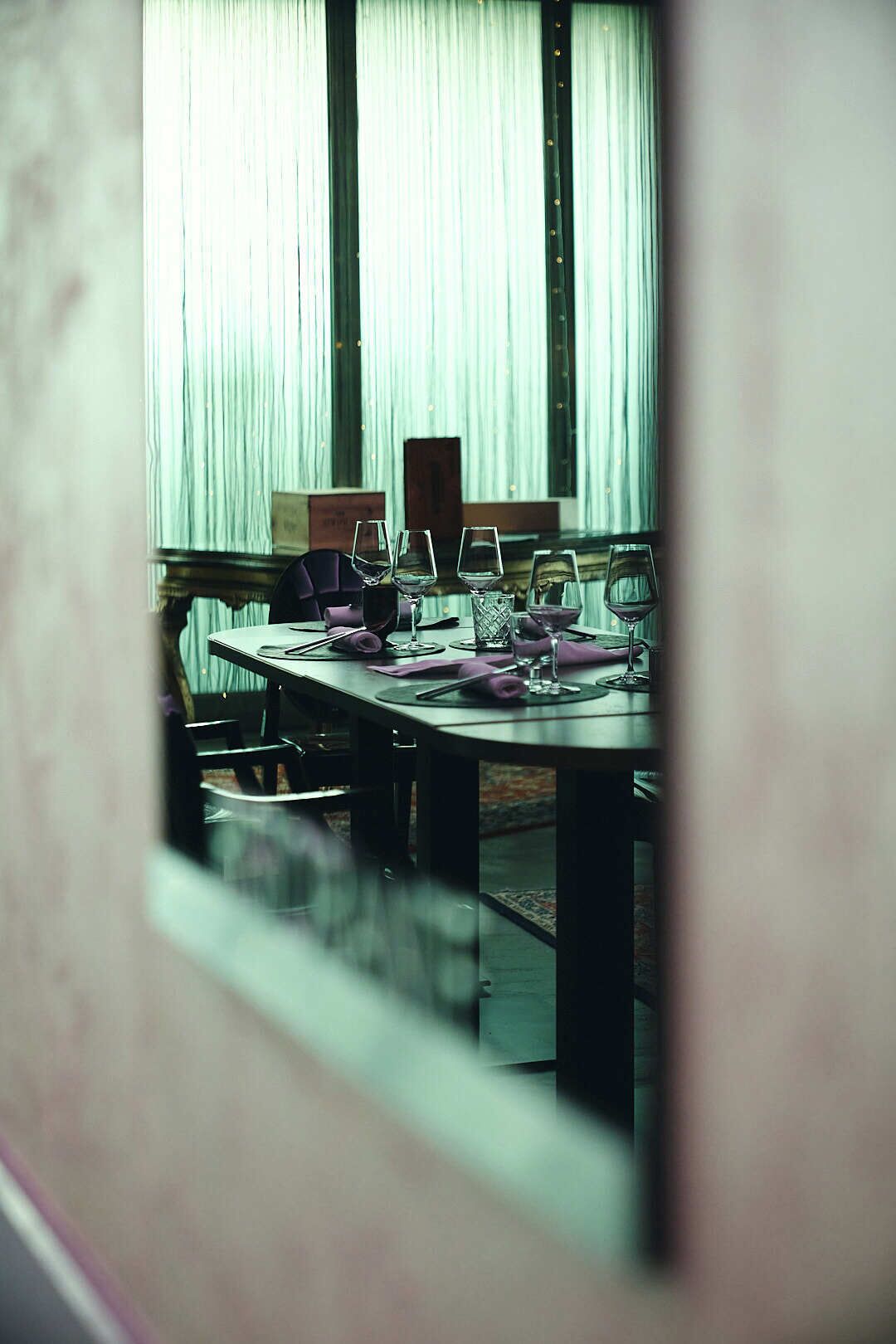Uma sala de jantar com uma mesa posta para quatro pessoas, com copos de vidro transparente e mesa de madeira.