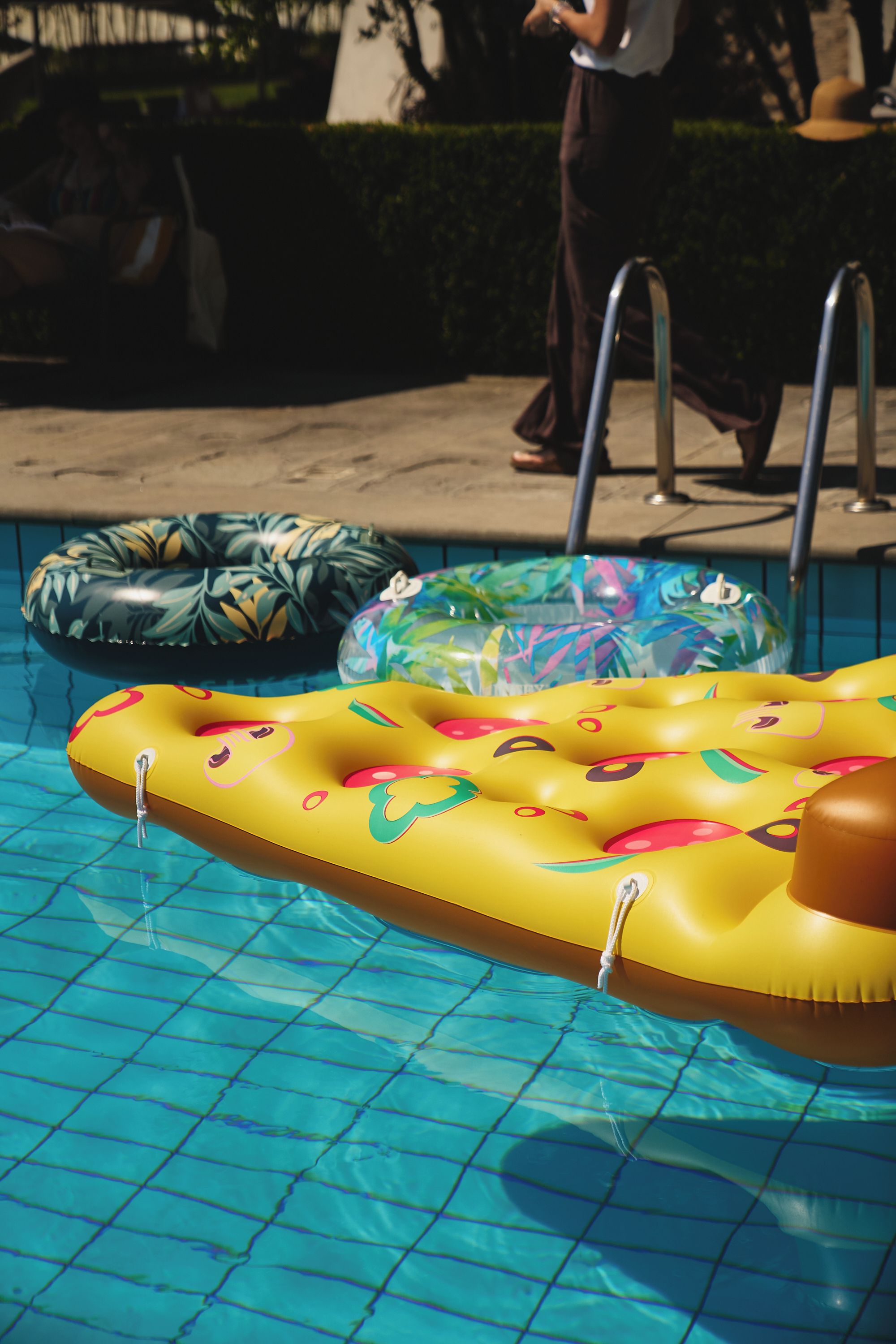 Una piscina con flotadores inflables y una escalera de metal.