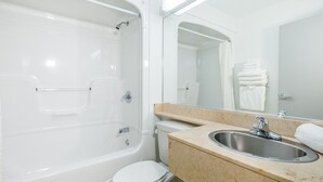 A bathroom with a bathtub, toilet, sink, and a mirror. - Repotel Henri IV Québec (Québec City)