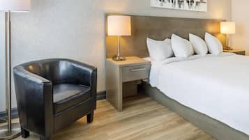 A hotel room with a bed, a chair, a nightstand, and a lamp.