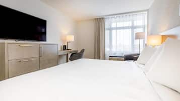 Habitación de hotel con una cama grande, un escritorio con silla, televisor y dos lámparas.