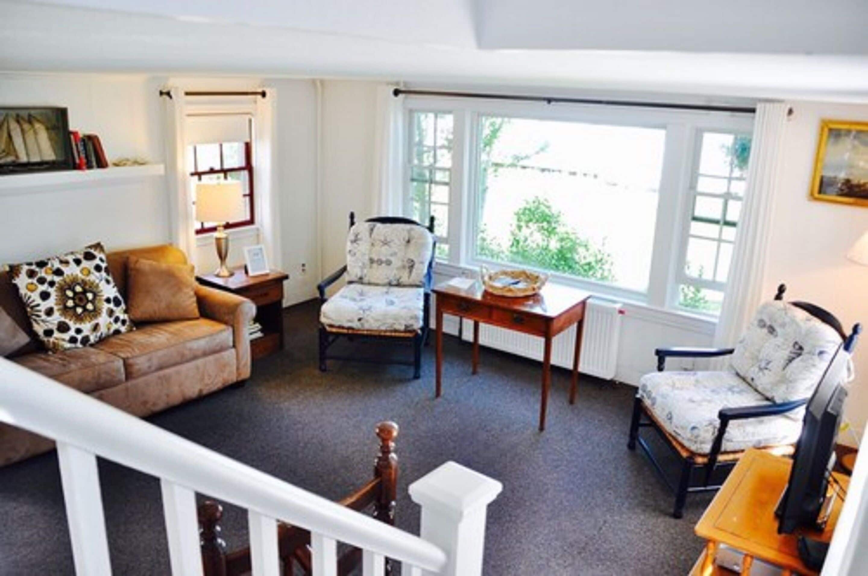 A cozy living room with a brown leather sofa, two patterned armchairs, a wooden coffee table, and a white radiator.