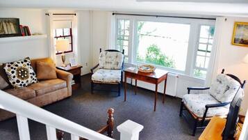 A cozy living room with a brown leather sofa, two patterned armchairs, a wooden coffee table, and a white radiator.