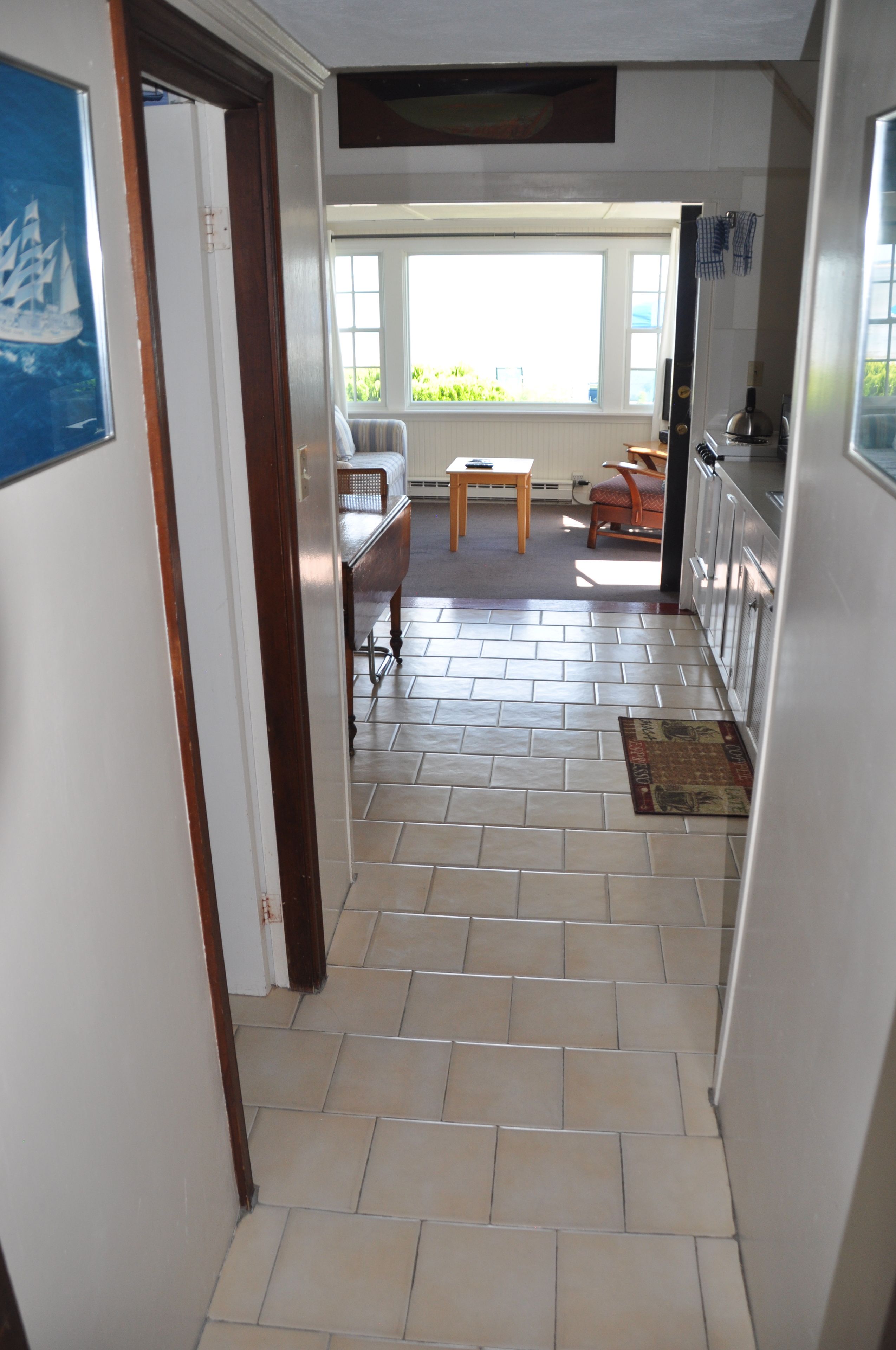 A hallway with a tiled floor leading to a dining area with a table and chairs.