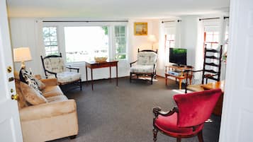 A living room with a beige sofa, a red chair, a wooden coffee table, and a television.