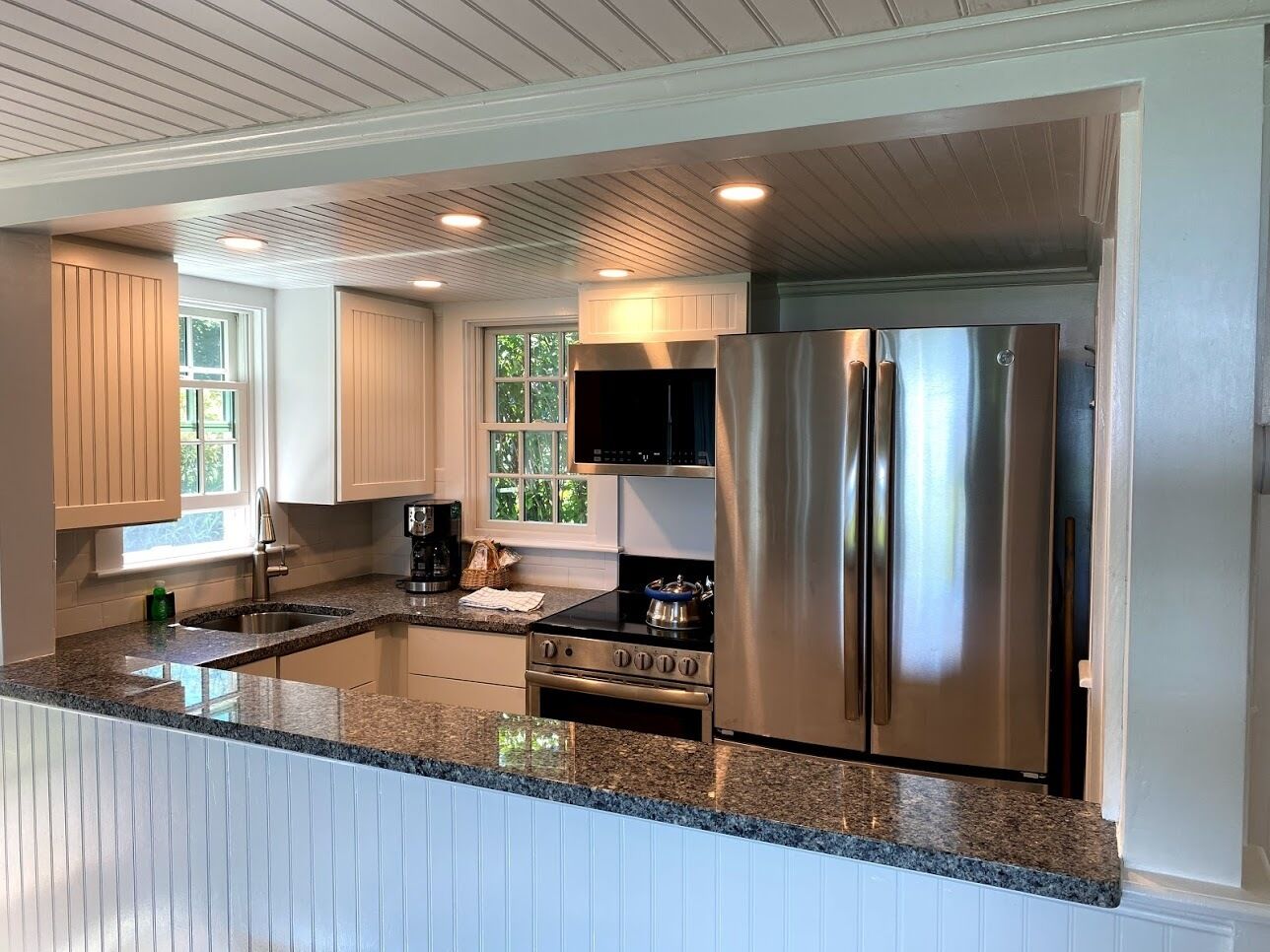 A modern kitchen with a stainless steel refrigerator, double sink, and built-in oven.