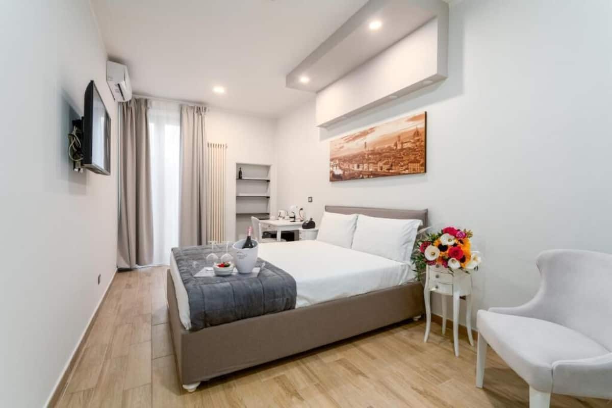 Una habitación de hotel moderna con una cama, un escritorio, una silla, un televisor y un cuadro en la pared.