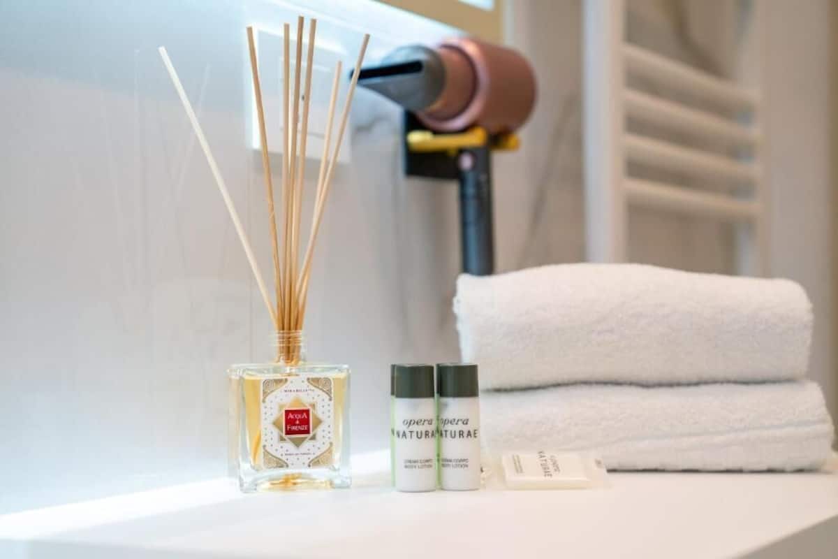 Un baño con una toalla blanca, una botella de Acqua di Parma y una botella de crema corporal opera opera.