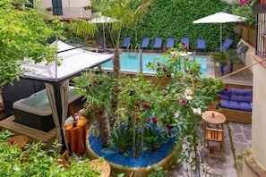 A poolside area with a hot tub, lounge chairs, and a small garden with blue pebbles and various plants. - Hotel Ginori al DUOMO (Florence)