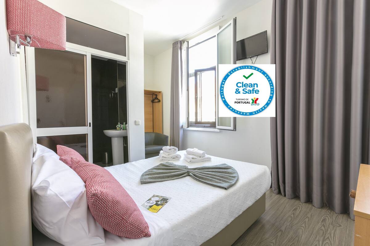 Una habitación de hotel con cama, televisión, ventana y baño.