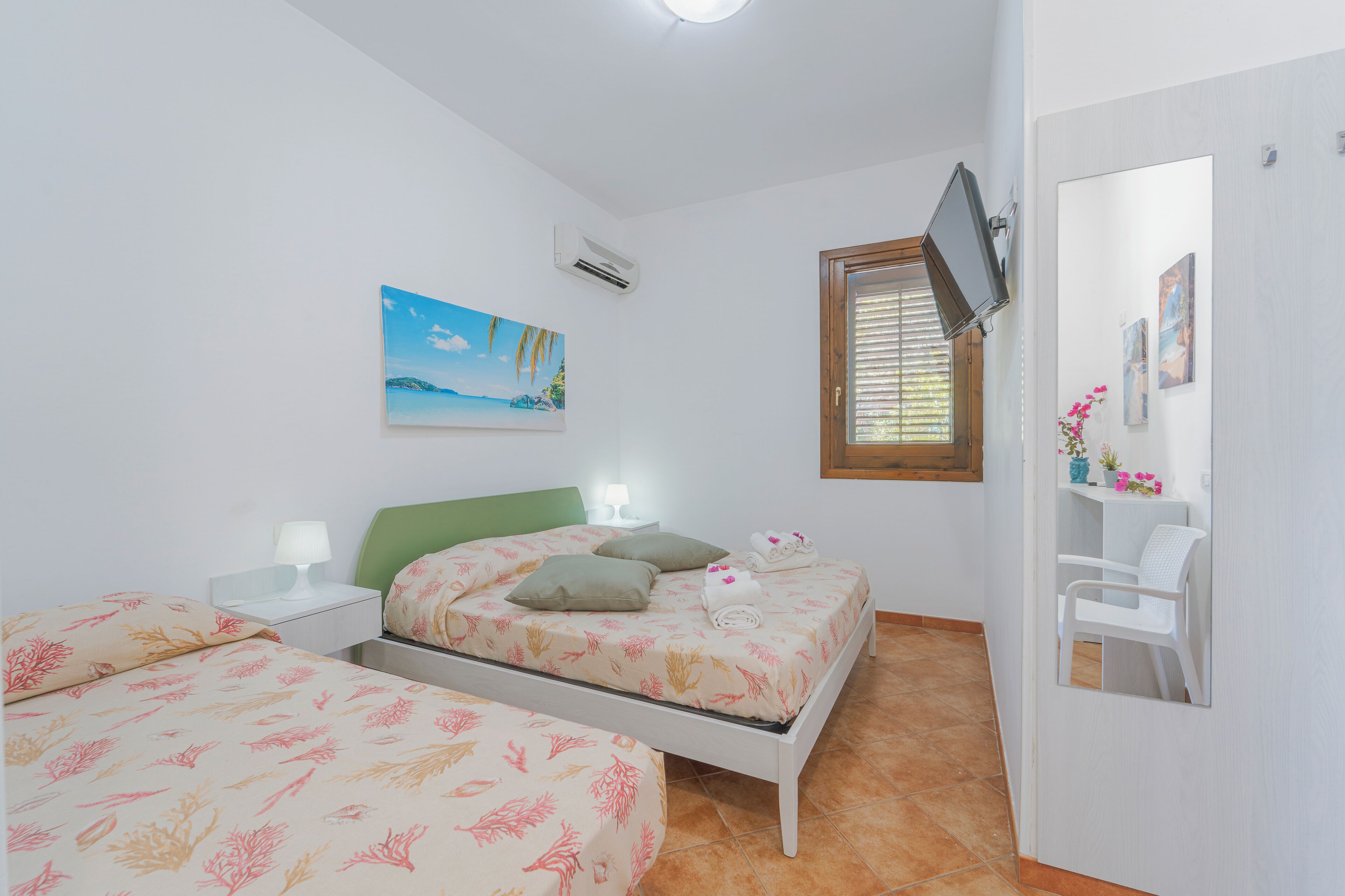 A bedroom with a bed, a nightstand, a TV, and a window.