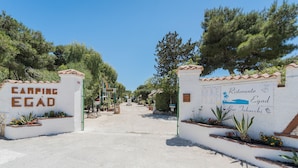 Un sendero que lleva a un edificio con un letrero que dice 'CAMPING EGAD' y otro letrero que anuncia 'Ristorante Egad Bar Tabacci'.