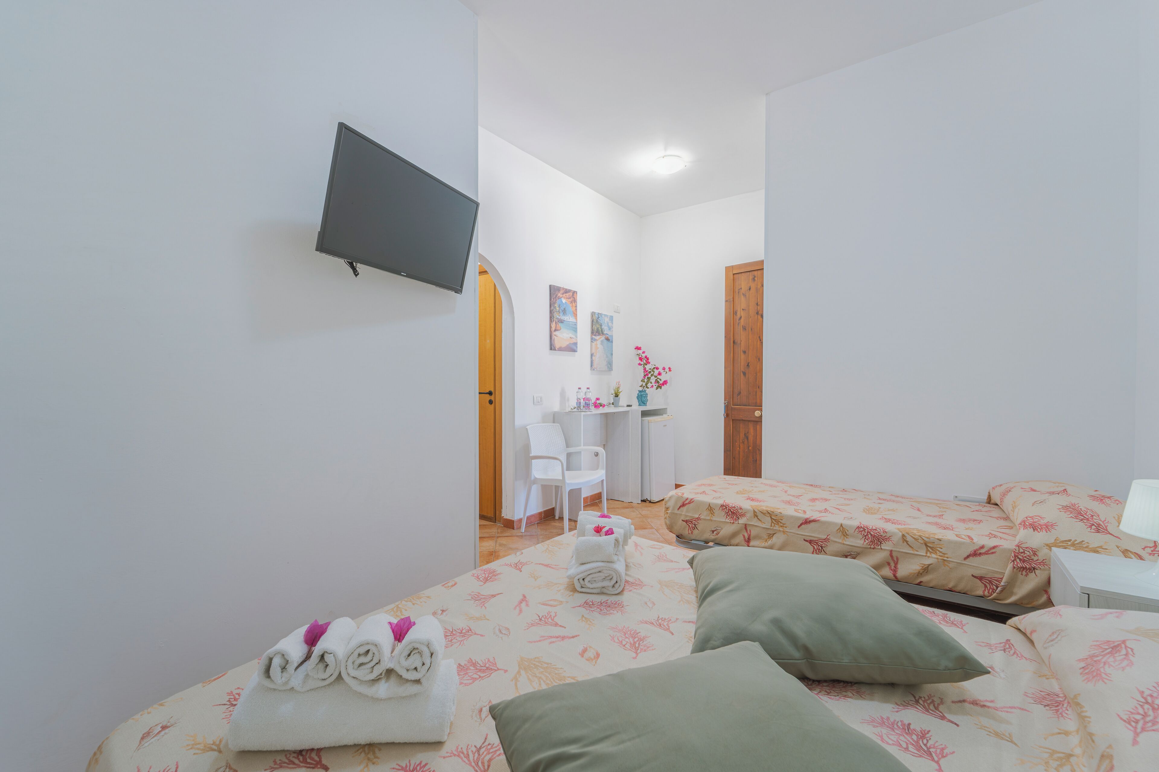 A hotel room with two beds, a TV, a desk, and a chair.