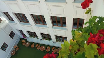 A multi-story building with a courtyard featuring outdoor seating and potted plants.