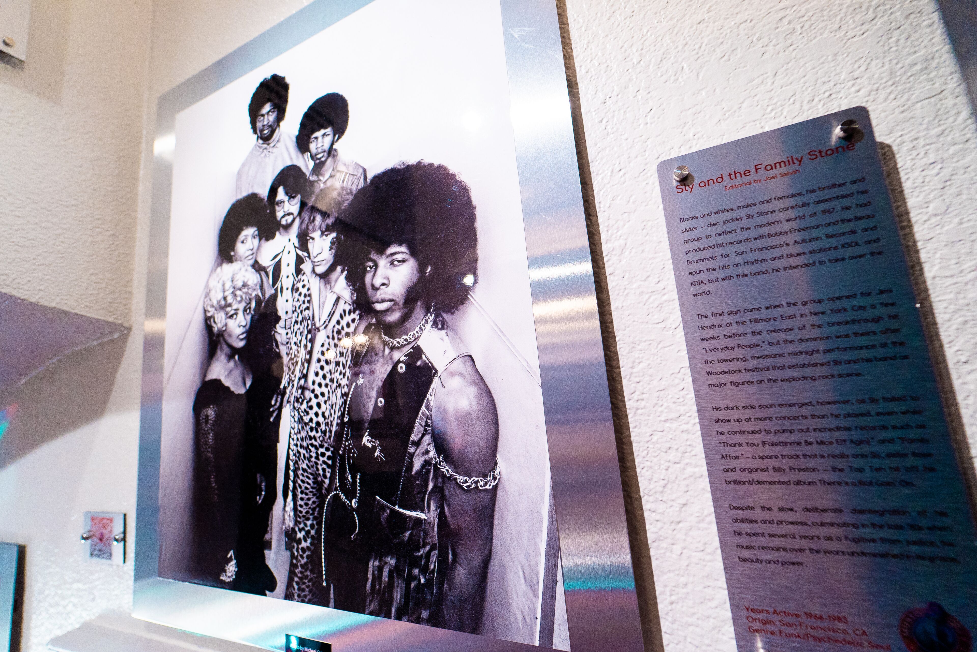 A poster of a band with a descriptive text panel beside it.