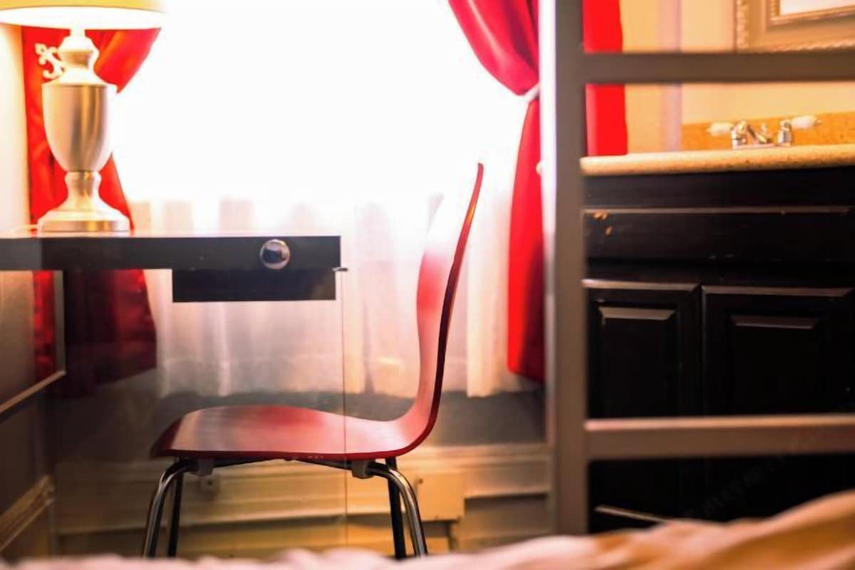 A room with a desk, chair, and a window with curtains.