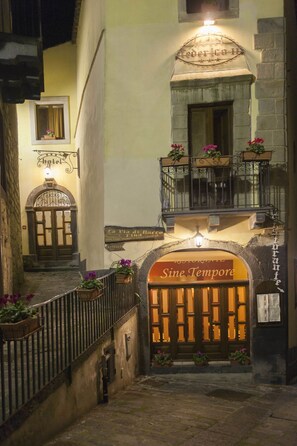 Ein Hotel Eingang mit einem Schild, auf dem 'Sine Tempore' steht, und einem Balkon mit Topfpflanzen.