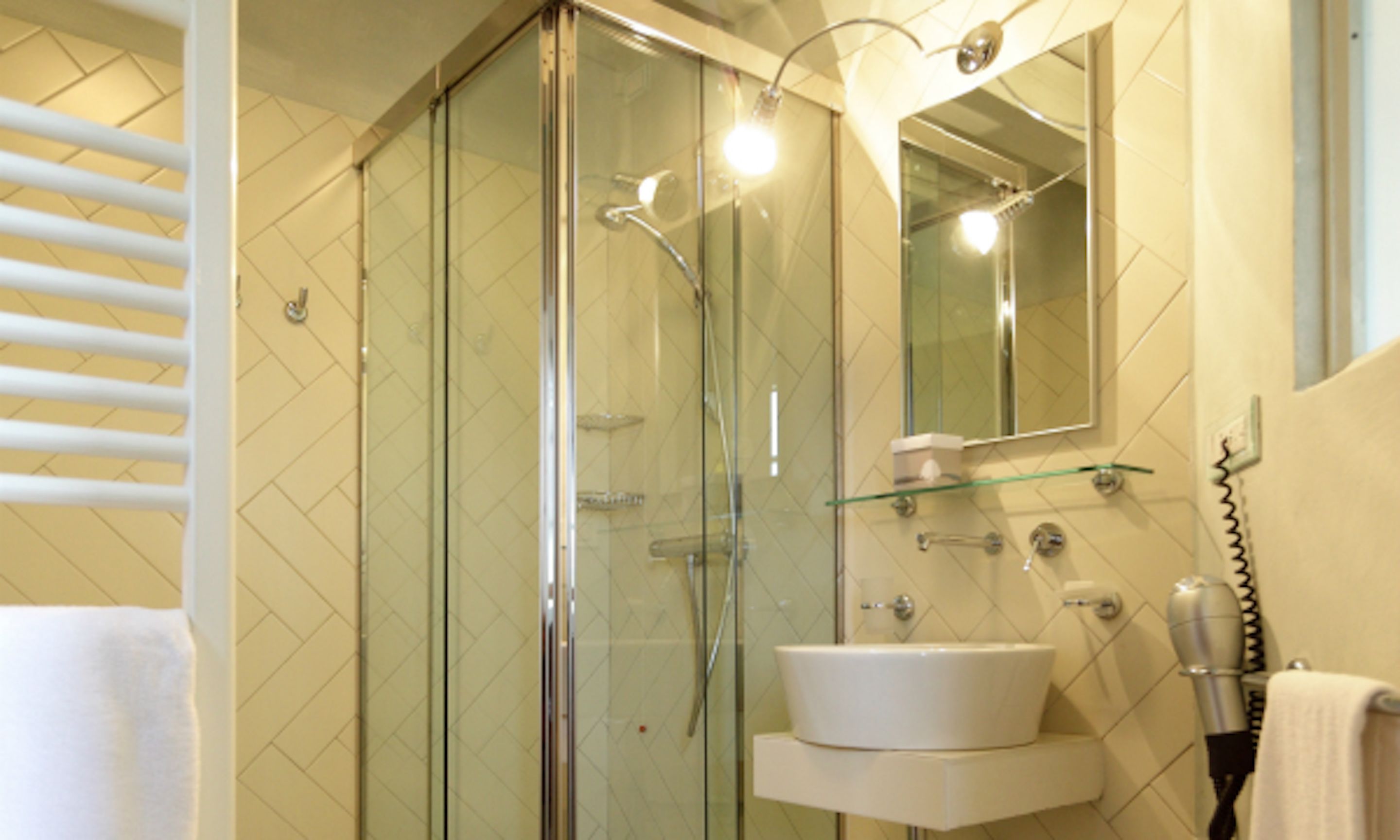 A modern bathroom with a glass-enclosed shower, a white sink, and a mirror above it.