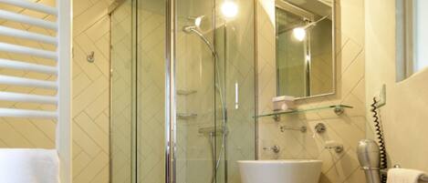 A modern bathroom with a glass-enclosed shower, a white sink, and a mirror above it.