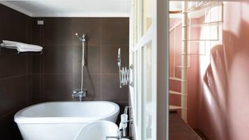 Un baño moderno con una bañera independiente, un cabezal de ducha y un inodoro.