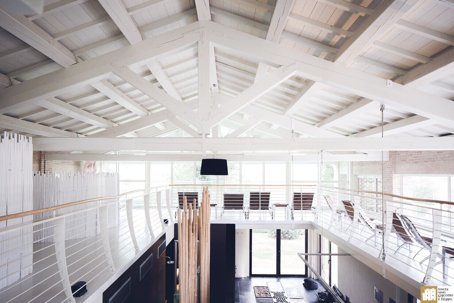 Un interior espacioso con un techo alto, ventanas grandes y una escalera que conduce a un nivel superior.