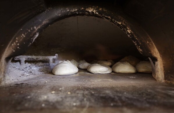 Un horno de ladrillo abovedado con varias hogazas de pan horneándose en su interior.