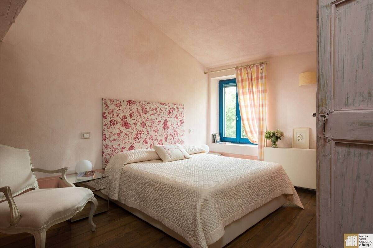 Une chambre à coucher avec un lit, une chaise, une fenêtre avec des rideaux et une porte.